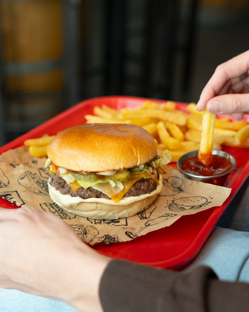 Burger maison avec frites croustillantes et ketchup, parfait pour une dégustation gourmande.