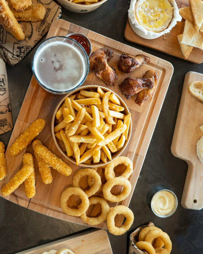 Plats de partage avec ailes de poulet, frites et onion rings.